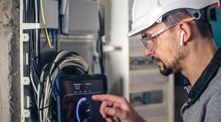 Man, an electrical technician working in a switchboard with fuses